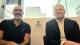Dr Nikolaos Souvlakis and Professor Damien Ridge taking a photo in front of the Westminster Community Counselling Service logo